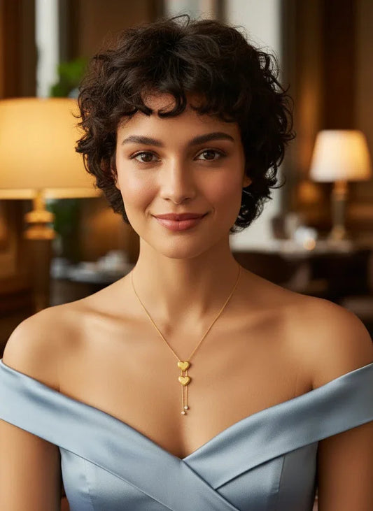 Woman wearing a light blue off-shoulder dress with a gold necklace in an indoor setting.