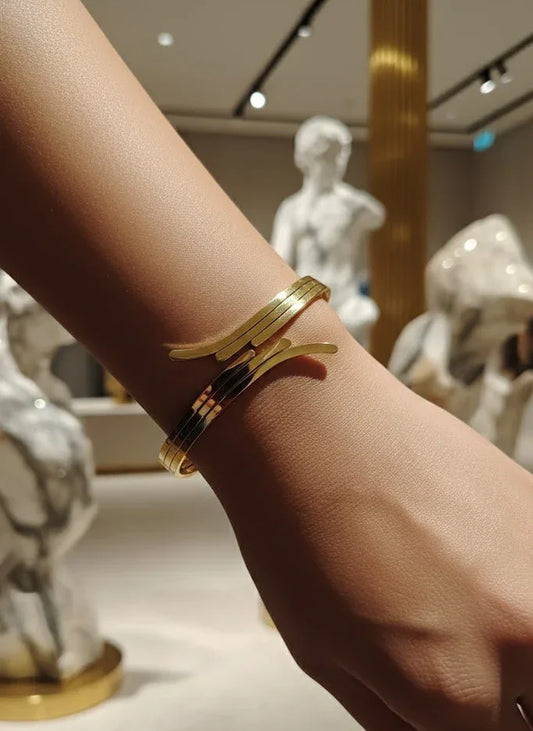 Gold bracelet on a wrist with a blurred background of sculptures