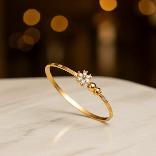 Gold bracelet with a diamond-like stone on a marble surface, blurred lights in the background