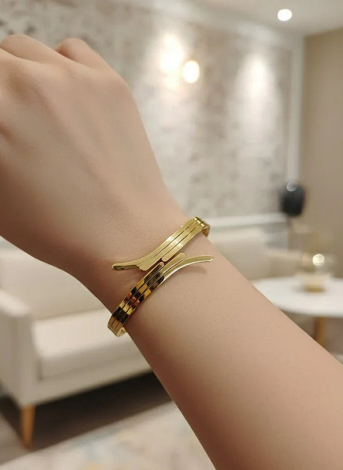 Gold bracelet on a wrist with a blurred indoor background